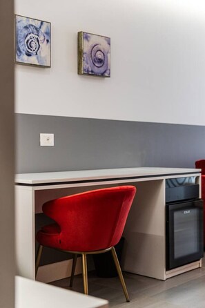 Eine moderne Küche mit einem Einbaukühlschrank, einem roten Stuhl und zwei abstrakten Bildern an der Wand.