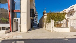 Uma rua urbana estreita com edifícios modernos, céu claro e portão fechado.