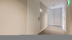 A hallway with beige walls, a carpeted floor, and a door with a handle. - Orange Studio 104 Love in Colours Collection (Durrës)