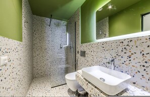 Ein Badezimmer mit Dusche, Toilette und Waschbecken, alles mit einem fleckigen Fliesenmuster.