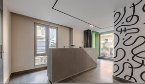 Eine moderne Hotelhalle mit einer Rezeption, großen Fenstern und einer grünen Akzentwand.