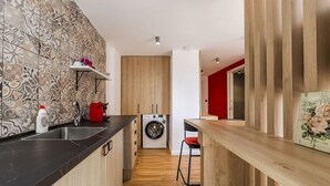 Uma cozinha moderna com máquina de lavar, armários de madeira e uma parede com detalhes vermelhos.