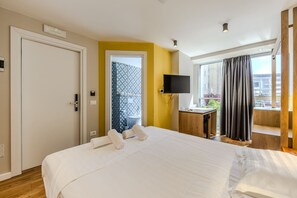 A hotel room with a bed, a TV, a desk, and a window with curtains. - Yellow Studio 106 Love in Colours Collection (Durrës)