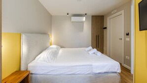 Una camera d'albergo con un letto, un comodino e un condizionatore d'aria a muro.