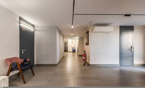 A modern hallway with a fire extinguisher, a scooter, and a chair. - Yellow Studio 106 Love in Colours Collection (Durrës)