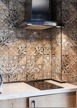 A kitchen with patterned tiles, a stainless steel range hood, and a wooden countertop. - Blue Studio 101 Love in Colours Collection (Durrës)
