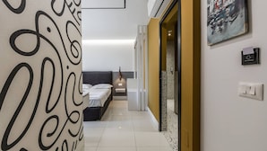 A modern hotel room with a bed, bedside table, and a large abstract artwork on the wall. - Golden Studio 117 Love in Colours Collection (Durrës)