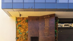 A modern building entrance with a brown wall, a staircase, and a glass facade. - Golden Studio 117 Love in Colours Collection (Durrës)