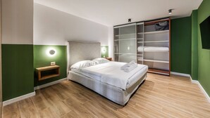 A modern bedroom with a bed, bedside table, and a built-in wardrobe. - Green Apartment 103 Love in Colours Collection (Durrës)
