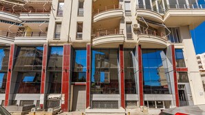 A multi-story building with balconies, large windows, and a modern architectural design. - Green Apartment 103 Love in Colours Collection (Durrës)