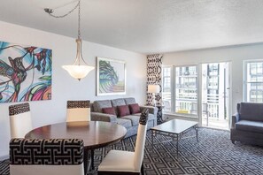 Ein modernes Wohnzimmer mit einer Couch, einem Esstisch und einem gemusterten Teppich.