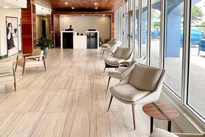 A hotel lobby with a reception desk, seating area, and large windows. - Cozy 1-bedroom apartment in delightful Surfside with AC and gym solara (Surfside)