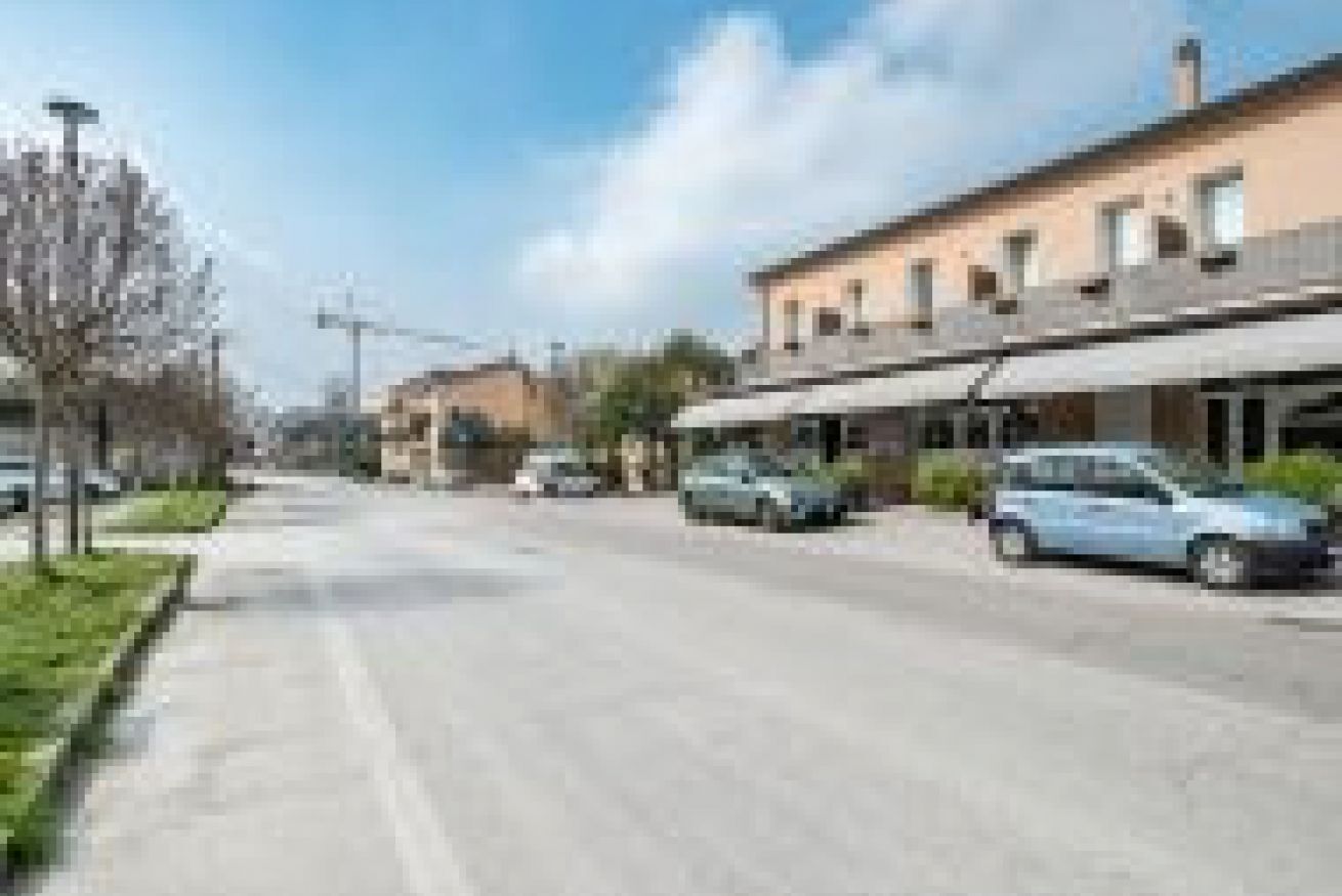 A street with buildings, cars, and a sidewalk.