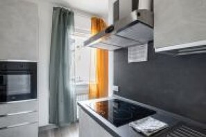 Una cucina moderna con forno integrato, microonde e un piano di lavoro con bollitore.