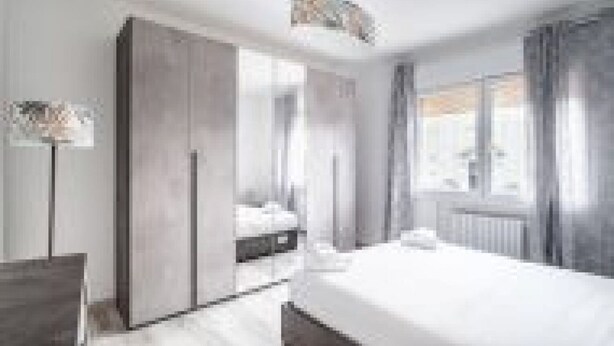 A modern hotel room with a large bed, a wardrobe, and a window with curtains. - GuestHost - San Vincenzo Apartment 2 Vigonza (Peraga)