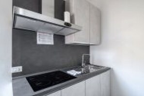 A modern kitchen with a built-in stove, a microwave, and a small sink. - GuestHost - San Vincenzo Apartment 2 Vigonza (Peraga)
