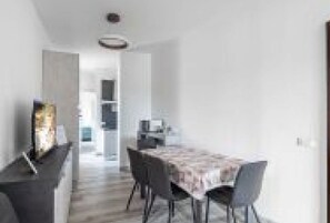 A dining area with a table and chairs, a kitchen in the background, and a hallway leading to another room. - GuestHost - San Vincenzo Apartment 2 Vigonza (Peraga)