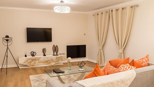 Una sala de estar con sofá, mesa de centro, televisor y lámpara de pie.