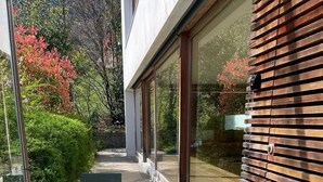 Zona exterior moderna amb seients, una cadira i taula, un pont de fusta i un estri de benvinguda.