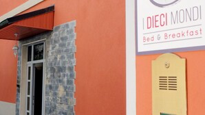 Een gebouw met een bord waarop 'DIECI MONDI Bed & Breakfast' staat en een deur met een raam.