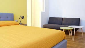 Een kamer met een bed, een bank, twee kleine tafels en een lamp.