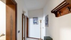 A hallway with wooden doors, a floor lamp, and a framed picture on the wall. - GuestHost - San Vincenzo Apartment 1 Vigonza (Peraga)