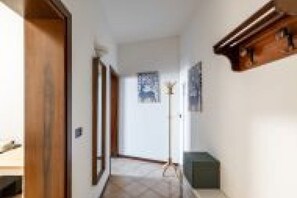 Um corredor com portas de madeira, um abajur e um quadro na parede.