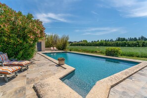 A swimming pool with lounge chairs and a stone deck.