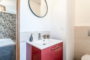 A bathroom with a white sink, red cabinet, and a mirror on the wall.