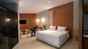 Una habitación de hotel moderna con una cama grande, un escritorio y un televisor.