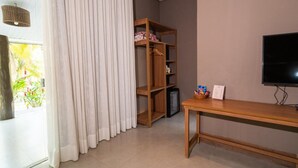 Una habitación con un armario de madera, televisión y una mesa con una cesta y papeles.