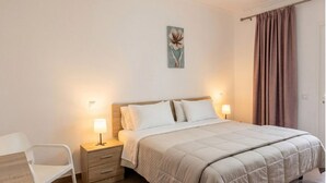 A bedroom with a bed, bedside tables, a chair, and a painting on the wall. - BUNGALOWS SUN CLUB (San Bartolomé de Tirajana)