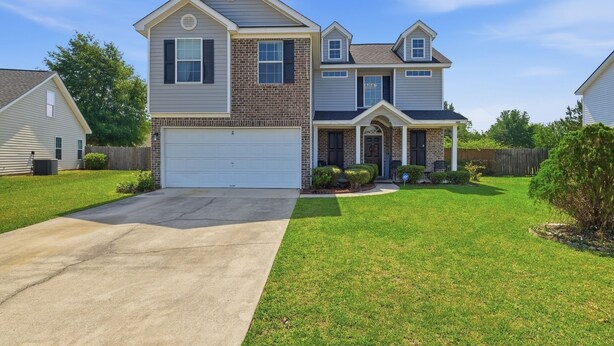 A two-story house with a garage, a front porch, and a well-maintained lawn. - Ideal Dream Getaway 4 Bedroom Home (Savannah)