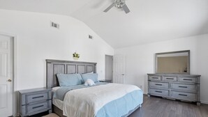 A bedroom with a bed, nightstands, a dresser, a mirror, and a ceiling fan. - Ideal Dream Getaway 4 Bedroom Home (Savannah)