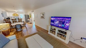 A living room with a TV, seating, a dining area, and a kitchen. - Venus 119 1 Bedroom Condo (Fort Walton Beach)