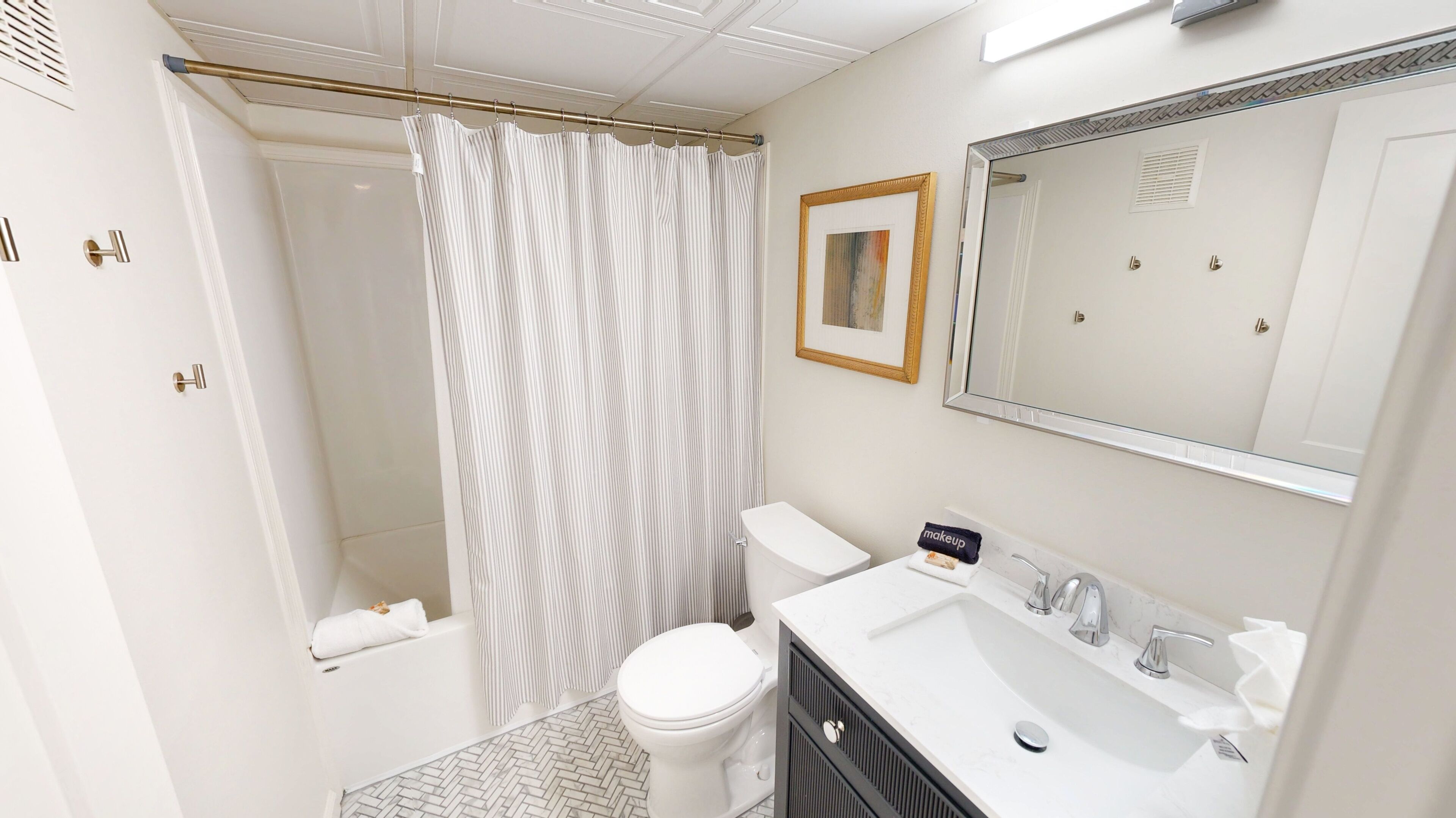 A bathroom with a shower, toilet, sink, and mirror.
