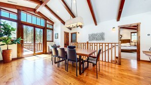A spacious dining area with a wooden table and chairs, large windows, and a view of the outdoors. - Graystone #2150 4 Bedroom Home (Mammoth Lakes)