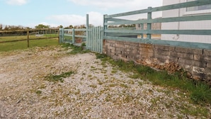 A gravel path leading to a gated area with a brick wall and a blue fence. - Moorland View (St Austell)