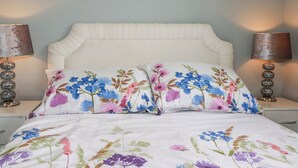 A bed with floral bedding, two bedside lamps, and a wall-mounted artwork. - Moorland View (St Austell)