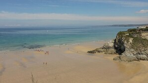 A beach with clear skies, calm waters, and rocky cliffs. - Moorland View (St Austell)