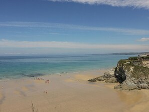 A beach with clear skies, calm waters, and rocky cliffs. - Moorland View (St Austell)
