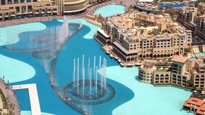 Ein großer Springbrunnen, ein mehrstöckiges Hotel und eine umgebende Stadtlandschaft.