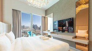 Ein modernes Hotelzimmer mit einem großen Bett, einem an der Wand montierten Fernseher und Blick auf die Stadt.