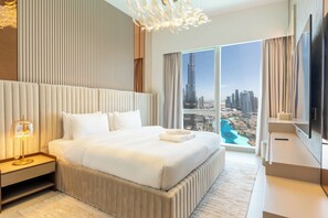 Una habitación de hotel moderna con una cama grande, televisión y vista a un paisaje urbano.