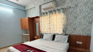 Un dormitorio con una cama, un armario de madera, un ventilador de techo y una ventana con cortina.