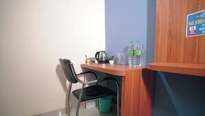 Una kitchenette pequeña con una silla, un hervidor y botellas de agua.