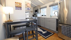 Cocina equipada con refrigerador, microondas, fregadero y taburetes de bar.