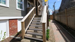 Una escalera de madera que lleva a una casa con base de ladrillo y valla de madera.