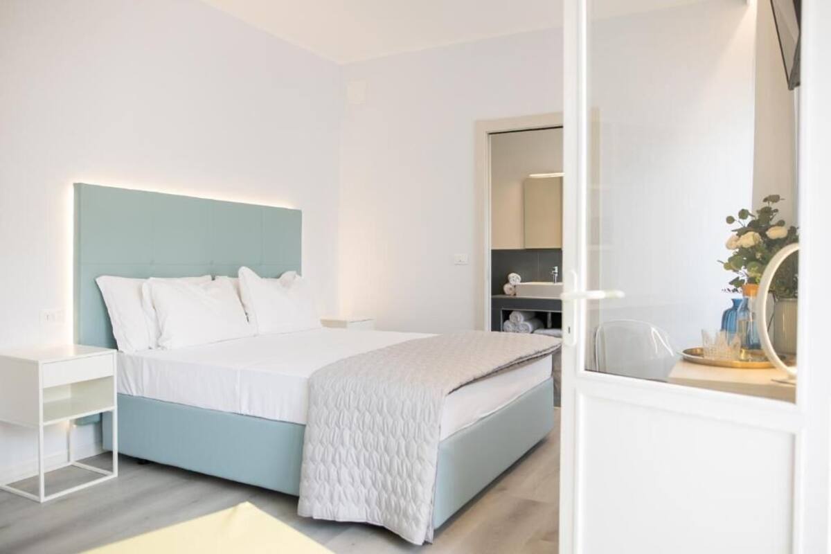 Un dormitorio moderno con cama, mesita de noche y espejo.