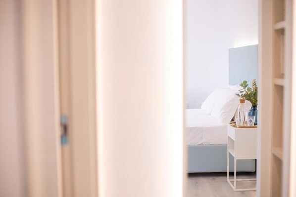 A bedroom with a bed, bedside table, and a nightstand with a vase and glassware.